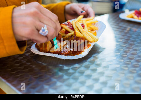 Donna di mangiare il tedesco Currywurst presso lo stand Foto Stock