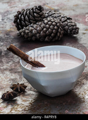 In casa del tè chai latte in un colore bianco porcellana ciotola con la stecca di cannella. Foto Stock