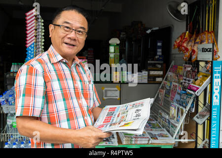 Uomo di mezza età la lettura in lingua cinese, giornale di Ipoh, Malaysia. Foto Stock