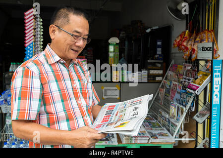 Uomo di mezza età la lettura in lingua cinese, giornale di Ipoh, Malaysia. Foto Stock