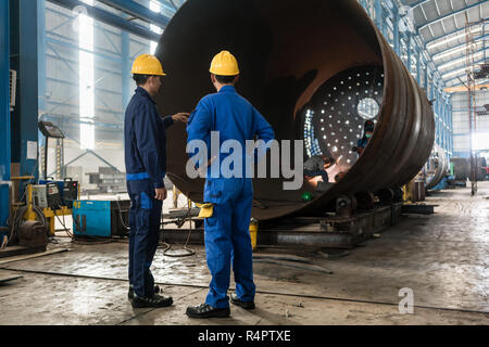 Lavoratori sorveglia la fabbricazione di un cilindro metallico Foto Stock