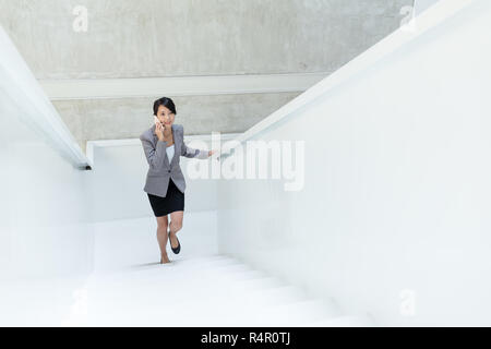 Imprenditrice salendo le scale e parlare al telefono cellulare Foto Stock
