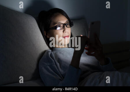 Donna che indossa gli occhiali e uso del telefono cellulare a casa Foto Stock