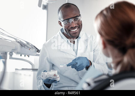 Bello medico internazionale consultando il suo giovane paziente Foto Stock