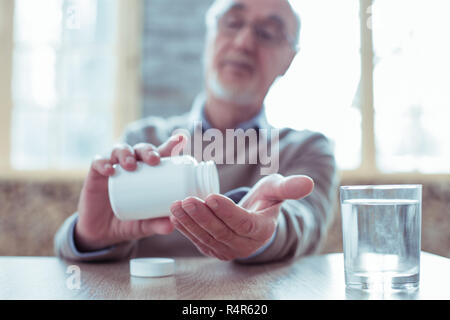 Attento uomo contando il suo pillole a portata di mano Foto Stock