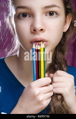 Bella ragazza guardando la telecamera tenendo matite colorate Foto Stock