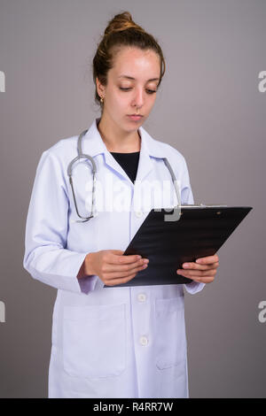 Giovane bella donna medico contro uno sfondo grigio Foto Stock