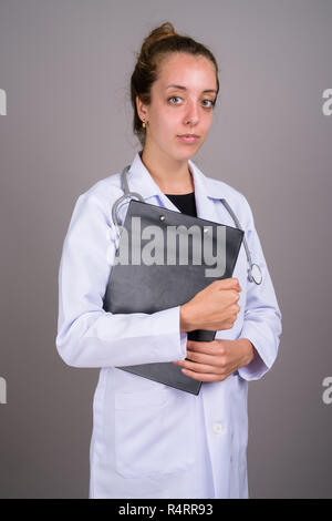 Giovane bella donna medico contro uno sfondo grigio Foto Stock