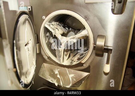 A ice cream factory è la pulizia gelatiera macchina da gelato residui. Preparazione di gelato. Foto Stock
