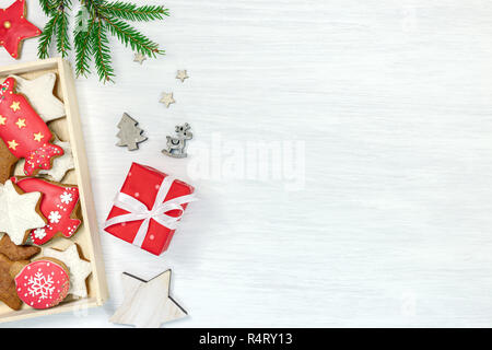 In inverno il concetto di festa con sfondo verde abete del ramo, box con natale fatti a mano gingerbread cookie e di oggetti di arredamento, appartamento vista laici Foto Stock