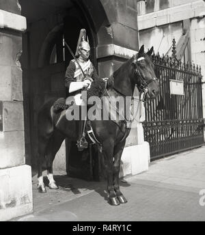 Anni sessanta, storico, un Queen's Life Guard della cavalleria della famiglia in servizio sul suo cavallo a una sentinella posto al di fuori del lato di Whitehall di Horseguards, un edificio storico e il quartier generale militare a Westminster, Londra, Inghilterra, Regno Unito. Foto Stock