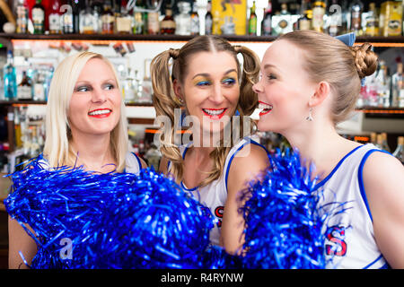 Gruppo di cheerleader girls watching un gioco della loro squadra preferita Foto Stock