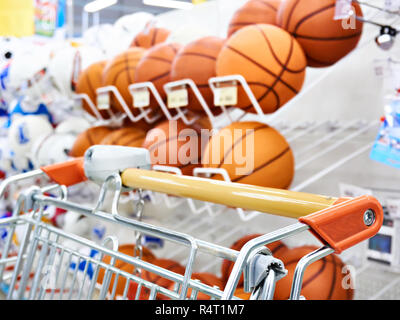 Carrello della spesa e basketballs nel negozio di sport Foto Stock