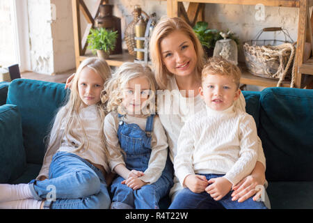 Madre di tre bambini seduti sul divano di casa. Foto Stock