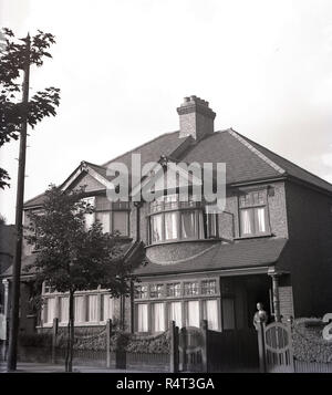 1940s, storico, una signora in piedi all'ingresso di un semi-detached casa a due piani casa suburbana, Inghilterra, Regno Unito. Costruito negli anni Venti del Novecento, la casa aveva una scatola di legno le finestre a battente e un Pebble Dash esterno. Foto Stock