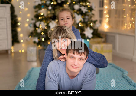 Famiglia giovane su un plaid blu nei pressi di albero di Natale Foto Stock