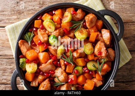 Delizioso pollo cucinato con verdure e rosmarino in salsa di melograno close-up in una padella sul tavolo. Parte superiore orizzontale vista da sopra Foto Stock