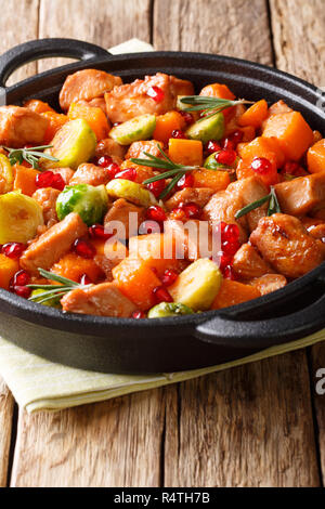 Spezzatino di pollo con le verdure e le erbe in una salsa di melograno close-up in una padella sulla tavola verticale. Foto Stock