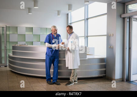 Medici di sesso maschile a discutere di record medico in ospedale Foto Stock