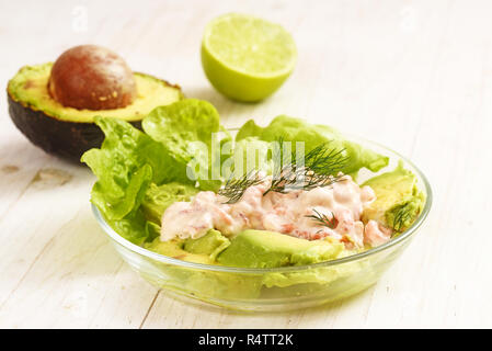 Insalata di lattuga, granchi in crema e di avocado in una ciotola di vetro su un dipinto di bianco di tavola di legno, selezionato soft focus, profondità di campo ridotta Foto Stock