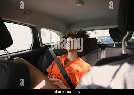 Stanco giovane donna che dorme nel sedile posteriore della macchina Foto Stock