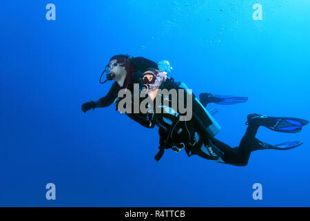 Due subacquei, uomo e donna, nuoto in acque blu, Mar Rosso, Egitto Foto Stock