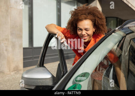 Ritratto sorridente, fiducioso giovane donna winking, arrivare in auto Foto Stock