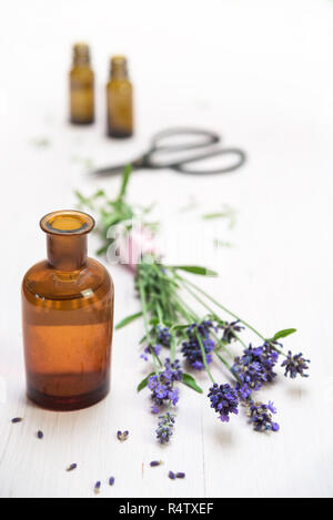 Fiori di lavanda e bottiglie con erbe essenziali Olio su legno, verniciate bianche, spazio copia, verticale, messa a fuoco selezionata, molto stretta la profondità di campo Foto Stock