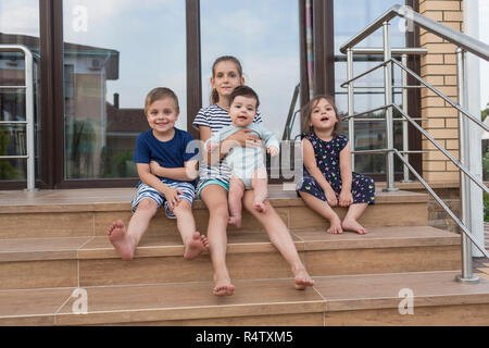 Ritratto a piedi scalzi fratelli e sorelle seduti sul patio passi Foto Stock