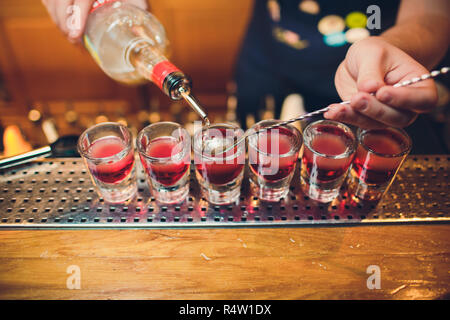 Il barista è tequila versatore in vetro contro lo sfondo della barra. Foto Stock