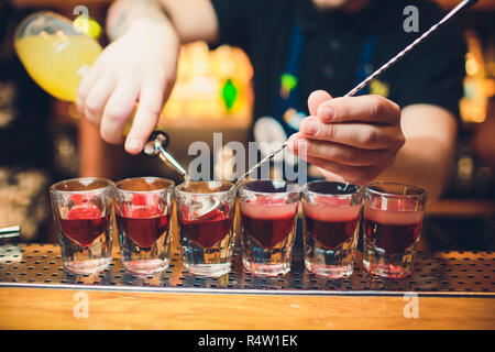 Il barista è tequila versatore in vetro contro lo sfondo della barra. Foto Stock