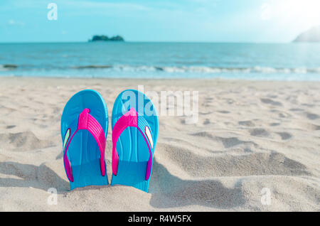 Colorato flip flop sulla spiaggia contro il cielo sereno. Foto Stock