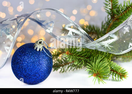 Blu glitter palle di Natale, ramo di albero di abete e nastro argentato su sfondo bianco con copia spazio per il testo.Il fuoco selettivo. Foto Stock