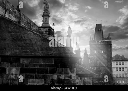 Con una forte e suggestiva di retroilluminazione, una vista del Ponte Carlo con silhouette di diverse statue barocche e raggi di sole attraverso le sculture Foto Stock