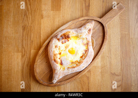 Aprire Adjarian khachapuri con formaggio e uova sulla tavola di legno. Tradizionale cibo caucasica Foto Stock