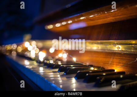 Tastiera di pianoforte illuminato con luci di Natale. Romantica musica di sottofondo Foto Stock