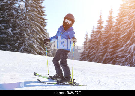 Piccolo Ragazzo nel casco sci sul pendio a mountain ski resort Foto Stock