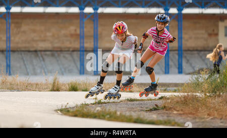 Due ragazze formazione nel pattinaggio di velocità sui rollerdrome nella serata estiva Foto Stock