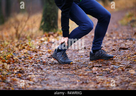 Runner maschio toccando cramped vitello a fare jogging al mattino. Riparazione del tendine di Achille il dolore o lesioni concetto sfondo Foto Stock