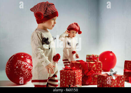 Ritratto di gioiosa twin-elfi tra enormi regali di Natale Foto Stock