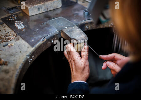 Gioielliere lavorando con un ago file un anello d'oro su un vecchio banco in autentici gioielli workshop Foto Stock