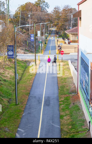 LINCOLNTON, NC, Stati Uniti d'America-11/25/18: una giovane coppia con il cane a camminare su una passeggiate/percorso in bicicletta. Foto Stock