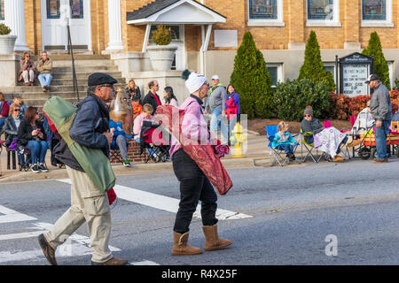 LINCOLNTON, NC, Stati Uniti d'America-11/25/18: una coppia senior trasportare sacchi con sedie pieghevoli prima di una parata locale. Foto Stock