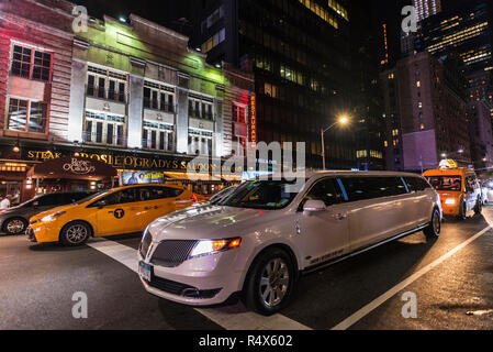 La città di New York, Stati Uniti d'America - 30 Luglio 2018: Bianco limousine e taxi di notte sulla Settima Avenue (7th Avenue) accanto a Times Square con le persone intorno a Manha Foto Stock