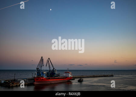 BALCHIK, Bulgaria - 17 settembre 2018: medie red nave da trasporto nelle calme acque del mare viene caricata al Black Sea port da due gru in estate eveni Foto Stock