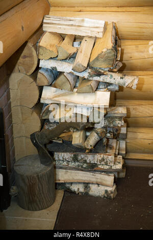 Un'ascia e un mucchio di trito di legno di betulla vicino alla stufa in bagno Foto Stock