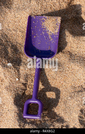 Una vista ravvicinata di una piccola forcella viola in spiaggia di sabbia in una bella e soleggiata giornata d'estate Foto Stock