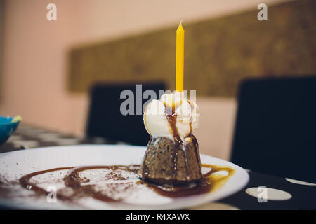 Tortina di compleanno con una candela rossa e colorata spruzza. Foto Stock