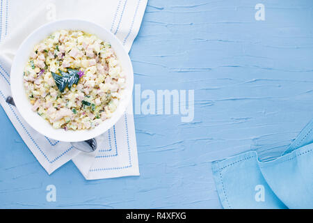 Insalata russa in una piastra su uno sfondo blu. Spazio libero per il testo. Vista dall'alto. Tradizionale cibo festoso Foto Stock