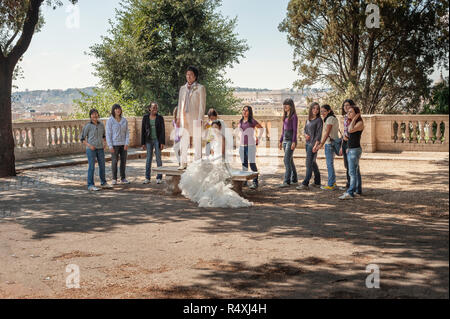 Oriental matura in posa per le fotografie del vostro matrimonio una posizione romantica nel Campo Marzio che si affaccia su Roma. Un gruppo di giovani turisti femmina a guardare. Foto Stock